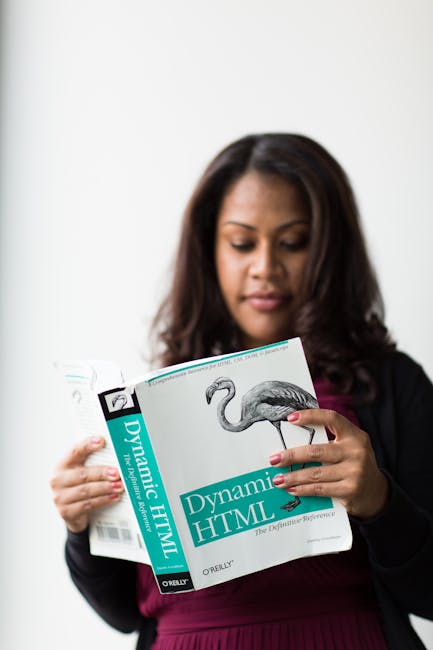 There is no image provided of a garden or outdoor scene; instead, the photo shows a woman with dark hair and a dark blazer, holding an open book titled 'Dynamic HTML' by O'Reilly, featuring an illustr